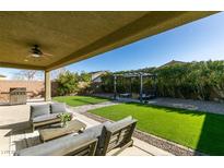 Relaxing backyard featuring a covered patio with outdoor seating and a lush lawn with a pergola at 124 Strone St, Henderson, NV 89012