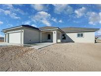 New construction home featuring stucco exterior, an attached garage and new concrete porch in an undeveloped lot at 1580 S Tiptop Trl, Pahrump, NV 89048