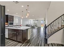 Spacious kitchen with granite island and stainless steel appliances that opens to living area and staircase at 3096 Beaux Art Ave, Henderson, NV 89044