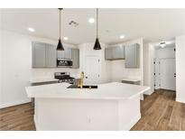 Bright kitchen featuring a large island, pendant lighting, stainless steel appliances, and wood-look floors at 4779 Straight Flush Dr # 103, Las Vegas, NV 89122
