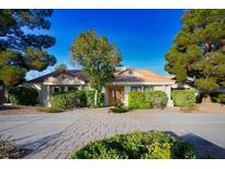 Charming single-story home featuring manicured landscaping, a brick driveway, and a tile roof at 8365 S Hauck St, Las Vegas, NV 89139