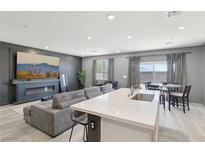Open-concept living room features a modern fireplace, TV and a spacious gray sectional couch at 9714 Harper Edge St, Las Vegas, NV 89143