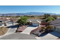Stunning aerial view of a single-story home with a well-maintained yard and beautiful mountain views in the distance at 5480 Lincolnwood Ct, Pahrump, NV 89061