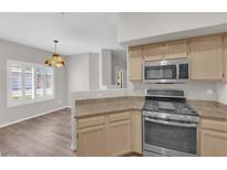 Bright kitchen featuring stainless steel appliances, light wood cabinets, and a stylish pendant light fixture at 6480 Annie Oakley Dr # 112, Las Vegas, NV 89120