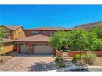 Beautiful two-story home with a three-car garage, terracotta roof, and lush landscaping at 10433 Ember Rose Ave, Las Vegas, NV 89135
