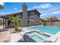 Backyard view of a pool and spa with a grey two-story home in the background at 1638 Candice St, Las Vegas, NV 89156