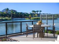A waterfront patio features a dining table with seating and wrought iron railing overlooking a serene lake and lush landscape at 20 Lakefront Dr, Henderson, NV 89011