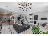 Bright living room featuring modern lighting, stylish decor, and an open floor plan to the kitchen and dining area at 7977 Texas Hills St, Las Vegas, NV 89113