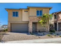 Two-story home featuring stacked stone accents, a gray two-car garage, and desert landscaping at 9588 Archer Peak Ct, Las Vegas, NV 89143