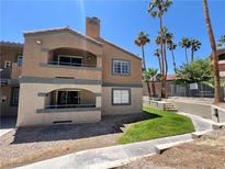 Two-story condo features stucco, balconies, and lush tropical landscaping at 5260 Mission Monterey Ln # 208, Las Vegas, NV 89107