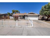 Charming single-story home with a white picket fence, lush landscaping, and a two-car garage at 5535 Oxbow St, Las Vegas, NV 89119