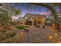 Beautiful backyard with brick patio, artificial grass, fire pit, ambient lighting, and mature trees at 5823 Falling Stream Ave, Las Vegas, NV 89131
