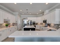 A spacious kitchen featuring white cabinets, quartz countertops, stainless steel appliances, and a stylish backsplash at 6131 Rio Vista St, Las Vegas, NV 89130