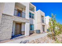 Charming townhome featuring a mix of stucco and stone facade, complemented by a black metal balcony and manicured landscaping at 6288 Dolosonte St, Las Vegas, NV 89113