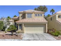 Tan two-story home featuring a terracotta-colored roof, two-car garage, and desert landscaping at 1833 Winners Cup Dr, Las Vegas, NV 89117