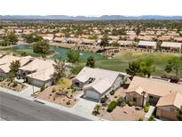Beautiful aerial view of a well-maintained community with lush landscaping, pond, and golf course in the background at 2816 High Range Dr, Las Vegas, NV 89134