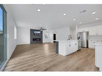 Bright living room with open floor plan, fireplace, ceiling fan and modern white kitchen at 8043 Tank Loop St, Las Vegas, NV 89166
