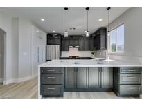 Modern kitchen features dark cabinetry, stainless steel appliances, and a large island with white countertops at 8108 Artistic Heights Ct, Las Vegas, NV 89143