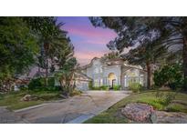 Stately two-story home featuring mature landscaping, large driveway, and lush green lawn at sunset at 2346 Villandry Ct, Henderson, NV 89074