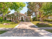 Elegant home showcasing a well-manicured lawn, mature trees, and a spacious driveway leading to a welcoming entrance at 2346 Villandry Ct, Henderson, NV 89074