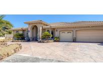 Stunning home features a tile roof, archway entrance, and three-car garage, surrounded by desert landscaping at 4011 Scott Russell Ct, North Las Vegas, NV 89031