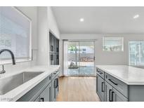 Bright kitchen featuring gray cabinets, stainless steel sink, and slider door leading to the backyard at 831 Purple Sage Ter, Henderson, NV 89015