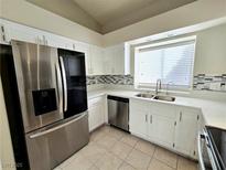 Bright kitchen featuring stainless steel appliances, white cabinetry, and a modern backsplash at 2035 E Warm Springs Rd # 1017, Las Vegas, NV 89119