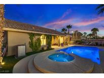 Inviting backyard featuring a sparkling pool, hot tub, lush greenery, and cozy patio under the twilight sky at 3088 Paseo Mountain Ave, Henderson, NV 89052