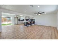 Bright, open-concept living room featuring a modern kitchen with a bar and wood-look flooring at 5200 Blanton Dr, Las Vegas, NV 89122