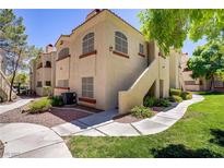 Inviting condo exterior featuring lush landscaping, stucco facade, and private entrance staircase at 525 Indian Princess Dr # 101, Las Vegas, NV 89145