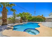 Inviting in-ground pool with a spa surrounded by lush landscaping and a white gravel perimeter at 5279 Consul Ave, Las Vegas, NV 89142