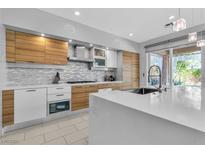 Modern kitchen featuring sleek wood cabinets, a spacious white countertop island, and stainless steel appliances at 556 Caribbean Palm Dr, Las Vegas, NV 89138