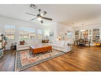 Bright living room featuring a large white sectional sofa, wood floors, ceiling fan, and an adjacent dining area at 715 Orange Plume Walk, Henderson, NV 89011