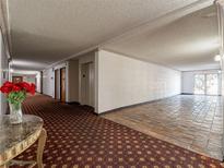 Condo hallway with patterned carpet and tile and an exit leading outside at 725 N Royal Crest Cir # 228, Las Vegas, NV 89169