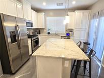 Bright kitchen features white cabinets, stainless steel appliances, granite countertops, and an island with bar stool seating at 8534 Insignia Ave # 101, Las Vegas, NV 89178
