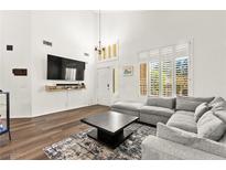 Bright living room with hardwood floors, large windows, modern furnishings, and a wall-mounted television at 8612 Danza Del Sol Dr, Las Vegas, NV 89128