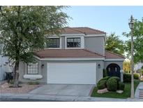 Charming home featuring a two-car garage, tile roof, and mature landscaping at 8740 Captains Pl, Las Vegas, NV 89117