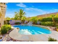 Backyard pool featuring a rock waterfall surrounded by mature landscaping at 8928 Rusty Rifle Ave, Las Vegas, NV 89143