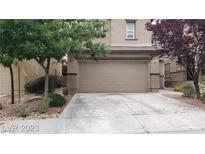 Two-car garage with a wide driveway and manicured trees in front of a two-story home at 167 Desert Pond Ave, Henderson, NV 89002