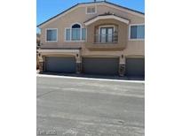 Exterior view of townhome with gray garage doors, second story balcony and neutral stucco finish at 3609 Indigo Flower St # 1, North Las Vegas, NV 89084