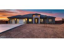 Stunning single-story home featuring a three-car garage and modern stone accents at sunset at 4740 W Agate Ave, Las Vegas, NV 89139
