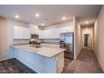 Bright kitchen features white cabinets, granite countertops, stainless steel appliances and a large island at 7517 Crested Moon St, North Las Vegas, NV 89084