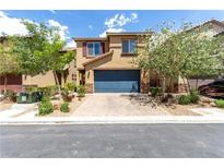 Beautiful two-story home with a blue garage door, landscaped front yard, and a brick driveway at 10086 Adina Ct, Las Vegas, NV 89141