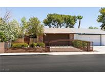 Charming single-story home with a brick facade, gated front yard, and mature trees at 3890 Lancome St, Las Vegas, NV 89115