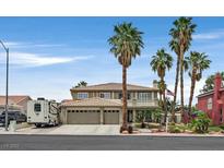 Two-story home showcasing a three-car garage, desert landscaping, and towering palm trees at 928 Aspen Valley Ave, Las Vegas, NV 89123