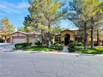 Charming single-story home with an arched entryway, a well-manicured lawn, mature trees, and a convenient two-car garage at 313 Glenridding St, Las Vegas, NV 89183