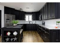 Modern kitchen with black cabinets, stainless steel appliances, and an island with seating, offers a stylish and functional space at 414 Crystal Canyon Dr, Mesquite, NV 89027