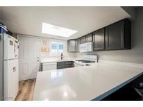 Bright kitchen with grey cabinets, white appliances, and quartz countertops with natural light from the skylight at 595 Sellers Pl, Henderson, NV 89011
