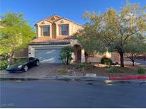 Charming two-story home with a tile roof, arched entryway, and a well-manicured front yard with mature trees at 11625 Cabo Del Verde Ave, Las Vegas, NV 89138