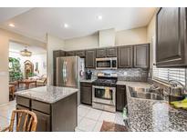 Well-lit kitchen featuring stainless steel appliances, granite countertops, and dark wood cabinetry at 310 Pissarro Pl, Henderson, NV 89074
